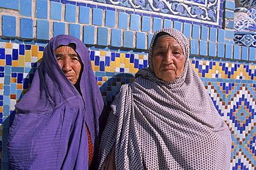 Uzbek women peek out from their veils in front of the tiled wall of the Blue Mosque, Mazar-i-Sharif, Balkh Province. The Blue Mosque is considered to be one of the most important and beautiful buildings in Afghanistan.  The region around Mazar-i-Sharif is the center of the Uzbek tribe in Northern Afghanistan