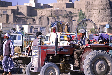 A tractor drives through a bustling market that flourishes below the old city walls in the town of Ghazni, Afghanistan.