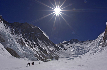 Climbers make their way to Advanced Basecamp (ABC) through the massive Western Cwm (glacial valley) on the Southeast Ridge route on Mt. Everest, Nepal. Everest's Southwest Face rises to the left with Lhotse and the Lhotse Face in the distance. Jake Norton, 4, 20, 2002, Western Cwm, Everest, Nepal.