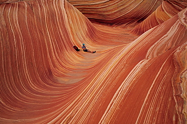 A desert hiker relaxes in the surreal landscape of a sandstone slot canyon in southern Utah, Arizona