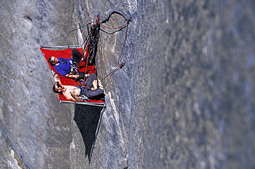 Beth Rodden and Tommy Callwell hang out on a rock ledge so Tommy can rest from rock climbing Dihedral wall, a multi pitch route on El Capitan in Yosemite National Park, California.