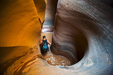 A man wading in water in sculpted slot canyon, Utah.