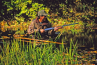 A duck hunter watches for game from his canoe on the Lamprey River, New Hampshire.