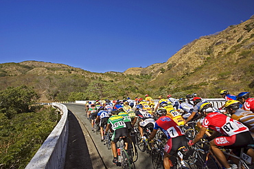 A large group of cyclers move in a pack through the mountains, Santiago de Cuba, Cuba. (blurred motion)