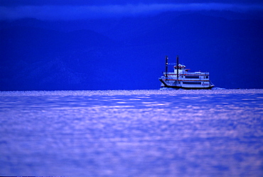 Paddleboat traveling on Lake Tahoe at sunset, California.