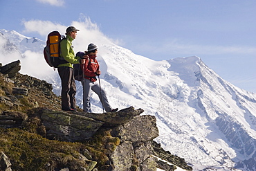 Two hikers stand on an overlook near Mont Blance in France.