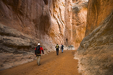 Three hikers in canyon, Arches National Park, Moab, Utah.