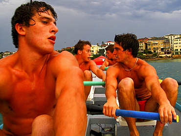 Three men onboard a surf boat in Sydney, Australia.