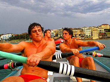 Three men onboard a surf boat in Sydney, Australia.