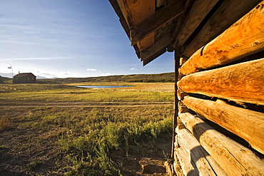 The side of log barn with ranch house in the backround on the Uncompahgre plateau, Colorado.