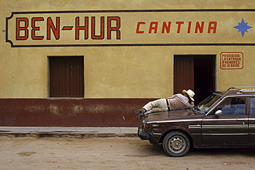 A patron of the Ben-Hur cantina relaxes on the hood of his car on a quiet afternoon in Trincheras, Mexico.