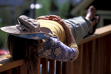 A woman napping on a railing with a hat over her face in Telluride, Colorado.