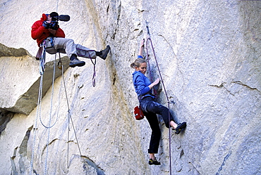 A man filming a woman lead climbing The Optimist in Smith Rock, Oregon.