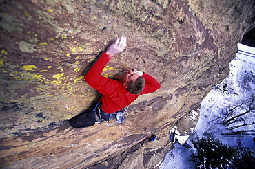 A man reaching for a hold while lead climbing near Boulder, Colorado (High Angle Perspective).