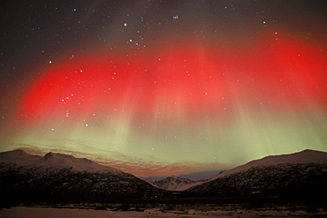 The aurora borealis (northern lights) shines with a rare, red and yellow hue above the Chugach Mountains in Alaska's Knik River Valley.