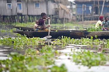 Woman with baby on back paddles canoe