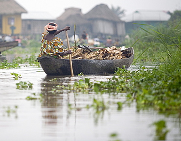 Woman paddles canoe filled with fire wood