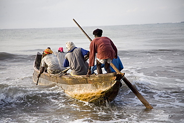 Fishermen in a boat getting into the ocean in Ghana