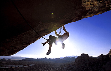 Man climbing on an overhang in Joshua Tree NP, California (Silhouette).