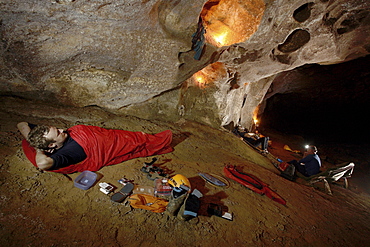 A cave explorer relaxing in his sleeping bag before having to get up and put on his cold wet clothes from the day before.