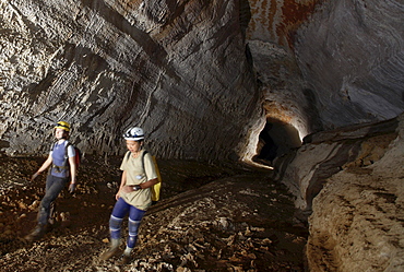 Two female cave explorers walk through a tunnel in a cave deep in the Malaysian jungle in Mulu.