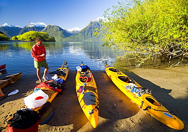 A stands next to kayaking gear in Lago Yelcho, Chile.