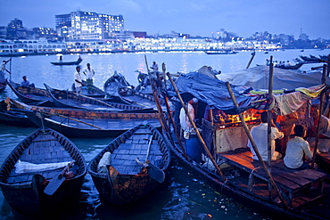 Dhaka,  Bangladesh - August 2011: Dusk at a floating tea shop along the busy Buriganga River (Old Ganges).  The heavily polluted river in the centre of Dhaka,  the capital of Bangladesh is a vital transportation hub in one of the busiest cites in Asia.