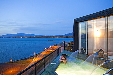 PUERTO NATALES, PATAGONIA, CHILE. A couple sits in an empty hot tub overlooking the waters surrounding Puerto Natales.