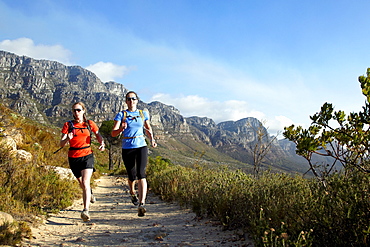 Katrin Schneider and Susann Scheller running on the Pipe Track above Camps Bay and below the Twelve Apostles. Cape Town, South Africa.