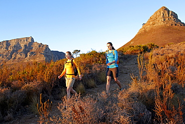 Katrin Schneider and Susann Scheller walking on the trail from Lion's Head to Signal Hill above the city of Cape Town just after sunrise. Cape Town, South Africa.