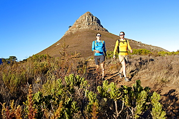 Katrin Schneider and Susann Scheller walking on the trail from Lion's Head to Signal Hill above the city of Cape Town just after sunrise. Cape Town, South Africa.