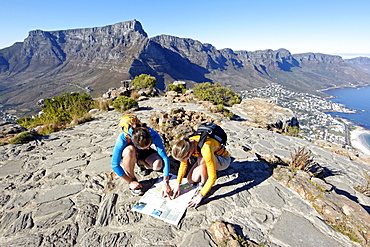 On top of Lion's Head with Table Mountain in the back Katrin Schneider and Susann Scheller are looking at a map of the city of Cape Town. South Africa.