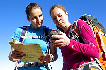 Katrin Schneider and Susann Scheller checking a handheld GPS device while hiking on an ocean trail between Gansbaai and De Kelders. South Africa.