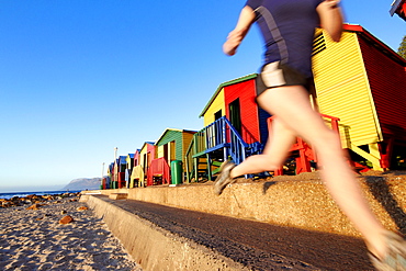 Katrin Schneider running past the famous and colorful bathing huts in St.James near Muizenberg. Cape Town, South Africa.