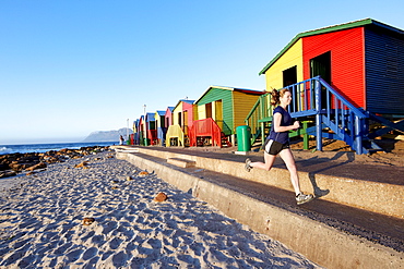 Katrin Schneider running past the famous and colorful bathing huts in St.James near Muizenberg. Cape Town, South Africa.