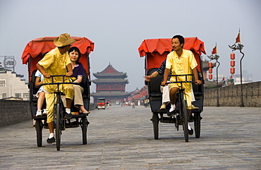 Rickshaw drivers carrying tourists on top of the Xian City Wall. Xian, Shaanxi Province. China