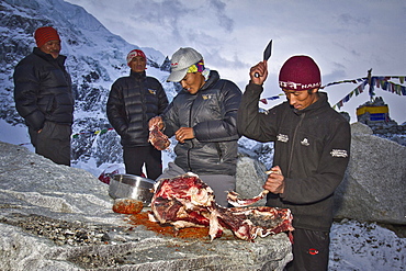 Two cooks for Jagged Globe Everest Expedition prepares Yak meat at Everest Base Camp while two sherpas watch