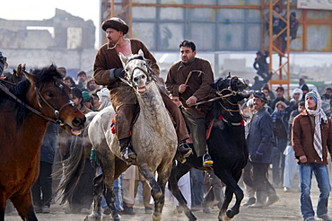 Afghan men on horseback turn their horses toward the action during a game of