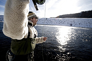 A man out fly fishing on a winter day.