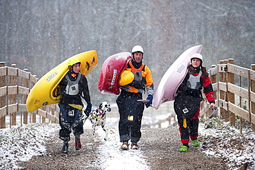 Three kayakers shoulder their kayaks in Tennessee.