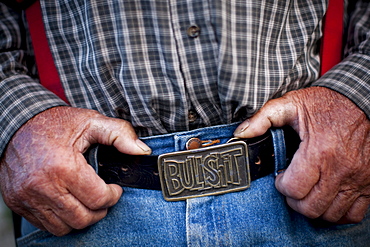 A rancher wears a belt buckle that reads