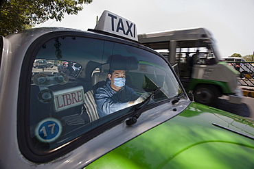 A taxi driver wears mask and plastic gloves inside his cab in Mexico City, DF, Mexico.