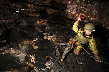 A young girl crawls on a ledge in a cave in China.