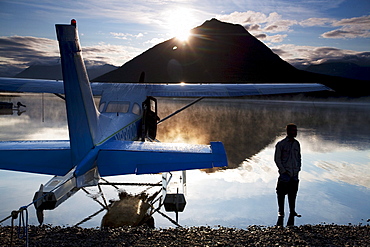 A man stands next to a float plane in Twin Lakes in Lake Clark National Park, Alaska.