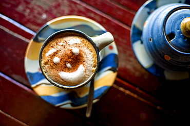 Close up photo of a cup of espresso with a smiling face made of foam.