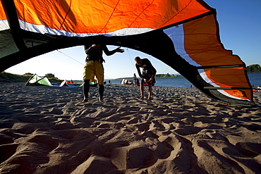 People (kiteboarders), kites and beach framed by a kite in nice light.