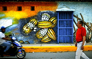 Men pass a street painting of cacao pods in Puerto Colombia, Venezuela.