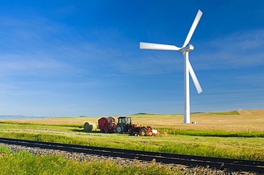 A single windmill spins over a framer's field alongside and old tractor. (blurred motion)