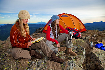 Two young women enjoy the view while camping along Sleeping Beauty in the Pacific Northwest