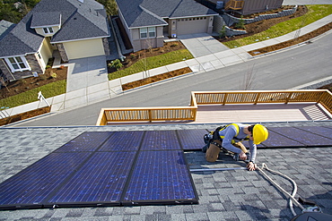 A worker installs solar panels on a rooftop in Redmond, WA.